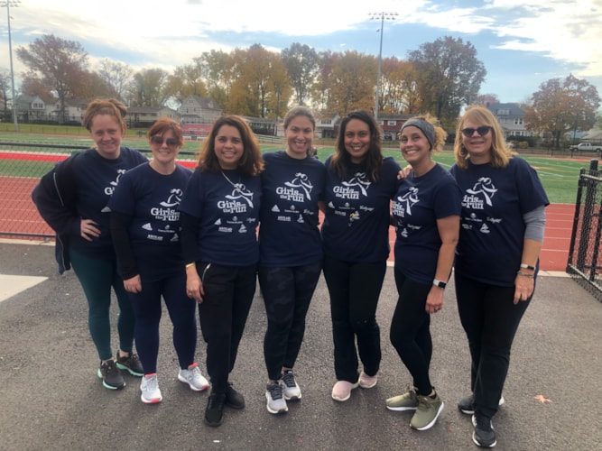 Smiling volunteers in dark blue Girls on the Run shirts 